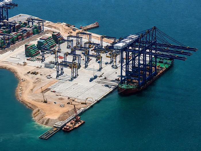 Λιμενικά έργα της Nafpliotis Bros σε προβλήτα container terminal με γερανούς, πλοίο και εμπορευματοκιβώτια